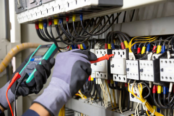 Electrician engineer tests electrical installations and wires on relay protection system. Adjustment of scheme of automation and control of electrical equipment.